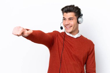 Beyaz arka planda izole edilmiş bir kulaklıkla çalışan beyaz pazarlamacı beyaz bir adam baş parmak işareti yapıyor.