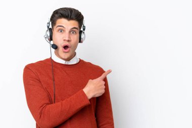 Tele pazarlamacı, beyaz arka planda izole edilmiş bir kulaklıkla çalışan beyaz bir adam şaşırmış ve işaret ediyor.