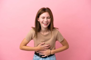 Pembe arka planda izole edilmiş genç İngiliz kadın, çok gülümsüyor.