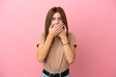 Pembe arka planda izole edilmiş genç bir İngiliz kadın elleriyle ağzını kapatıyor.