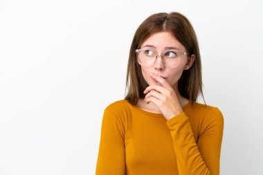Genç İngiliz kadın beyaz arka planda gözlüklü ve kuşkuları olan