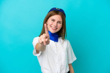 Uçak hostesi İngiliz kadın mavi arka planda izole edilmiş ve parmağını kaldırıyor.