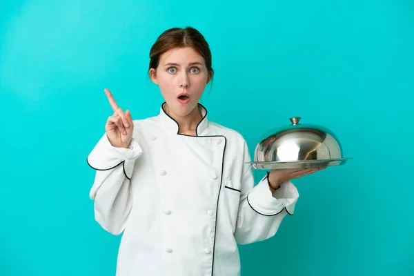 Young chef woman with tray isolated on blue background intending to realizes the solution while lifting a finger up