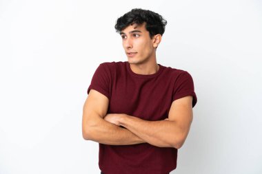 Arjantinli genç adam, beyaz arka planda izole edilmiş. Omuzlarını kaldırırken şüpheli hareketler yapıyor.