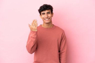 Arjantinli genç bir adam pembe arka planda izole edilmiş ve davet edilmişti. Gelmene sevindim.
