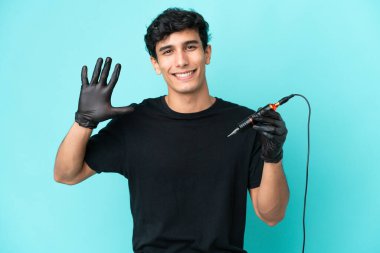 Dövme sanatçısı Arjantinli adam mavi arka planda izole edilmiş mutlu bir ifadeyle selamlıyor.