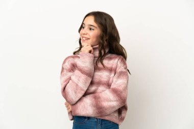 Beyaz arka planda izole edilmiş küçük beyaz kız yana bakıyor ve gülümsüyor.