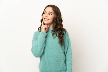 Beyaz arka planda izole edilmiş küçük beyaz kız yukarı bakarken bir fikir düşünüyor.