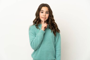 Beyaz arka planda izole edilmiş küçük beyaz kız sessiz bir jest işareti gösteriyor. Parmağını ağzına sokuyor.