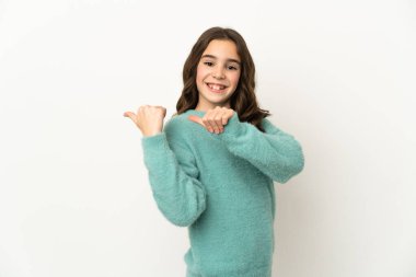 Beyaz arka planda izole edilmiş küçük beyaz kız bir ürünü sunmak için kenarı işaret ediyor.