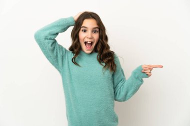 Beyaz arka planda izole edilmiş küçük beyaz kız şaşırdı ve parmağını yana çevirdi.