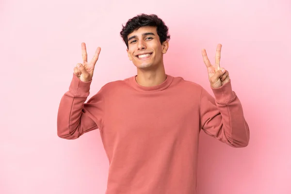 Молодой Аргентинский Мужчина Розовом Фоне Показывает Знак Победы Обеими Руками — стоковое фото