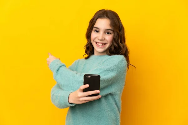 Pequeña Chica Caucásica Aislada Sobre Fondo Amarillo Usando Teléfono Móvil — Foto de Stock