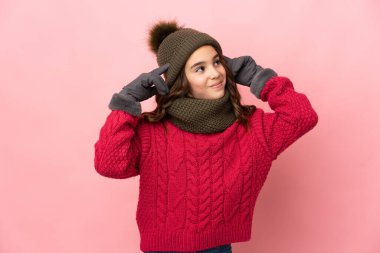 Kış şapkalı küçük kız pembe arka planda izole edilmiş kuşkuları ve düşünceleri var.