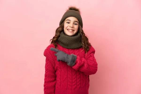 Liten Flicka Med Vinter Hatt Isolerad Rosa Bakgrund Pekar Sidan — Stockfoto