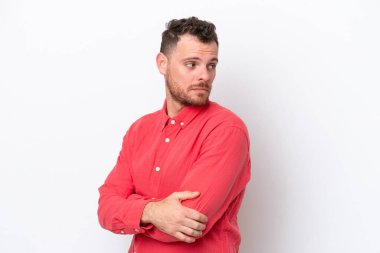 Beyaz arka planda izole edilmiş genç Brezilyalı adam kollarını çapraz tutuyor.