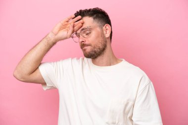 Young brazilian man isolated on pink background With glasses and tired