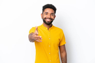 Beyaz arka planda izole edilmiş genç Brezilyalı adam iyi bir anlaşma için el sıkışıyor.