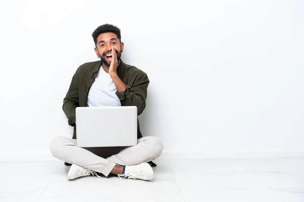 Joven Brasileño Con Portátil Sentado Suelo Aislado Blanco Gritando Con — Foto de Stock