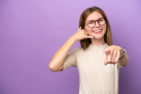 紫色の背景に孤立した若い英語の女性が電話ジェスチャーを作り 前を指す — ストック写真