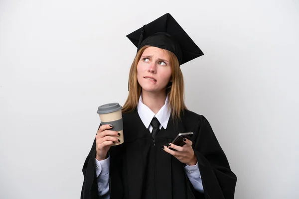 Young university graduate English woman isolated on white background holding coffee to take away and a mobile while thinking something