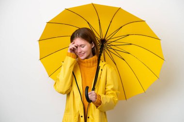 Yağmura dayanıklı ceketi ve şemsiyesi olan genç İngiliz kadın beyaz arka planda izole edilmiş gülüyor.