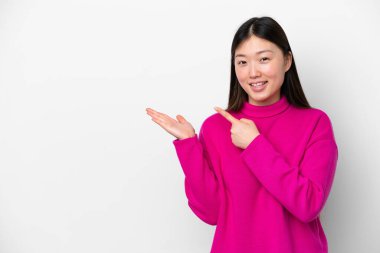 Beyaz arka planda izole edilmiş genç Çinli bir kadın bir ilan vermek için avucunun içinde hayali bir mekan tutuyor.