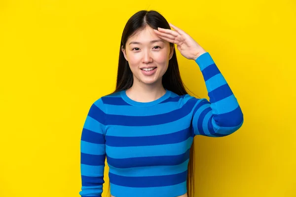 Молодая Китаянка Изолированная Желтом Фоне Салютует Счастливым Выражением Лица — стоковое фото
