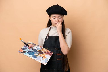 Genç Çinli ressam kadın bej arka planda izole edilmiş. Şüpheleri var.