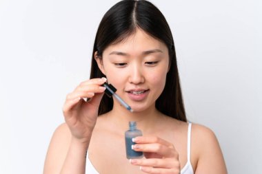 Genç Çinli bir kadın beyaz arka planda izole edilmiş, elinde bir serum tutarken gülümsüyor. Portreyi kapat