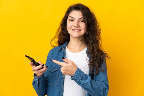 Ragazza Russa Adolescente Isolata Sfondo Giallo Utilizzando Telefono Cellulare Indicandolo — Foto Stock