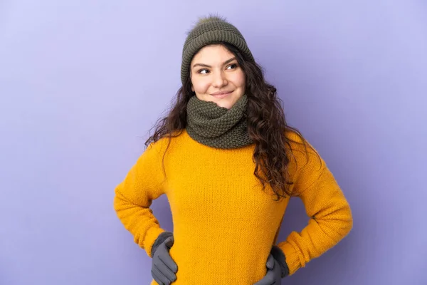 俄罗斯少女 头戴冬季帽 背景紫色 双手叉腰 面带微笑 — 图库照片