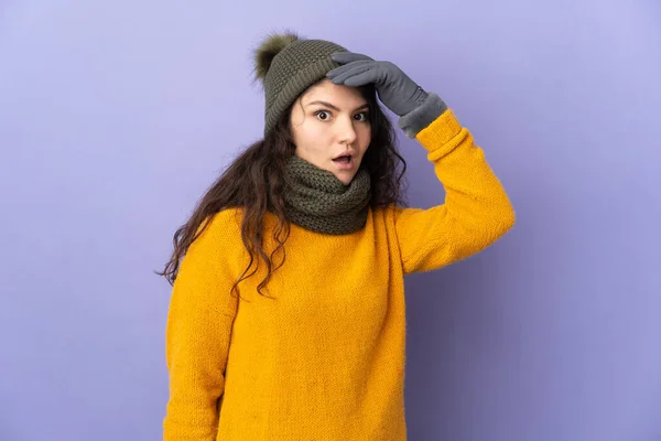 俄罗斯少女 头戴紫色背景的冬帽 望着侧面 做着令人惊讶的动作 — 图库照片
