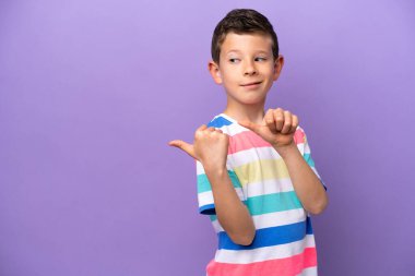 Mor arka planda izole edilmiş küçük çocuk bir ürünü sunmak için yan tarafı işaret ediyor.