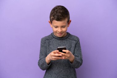 Mor arka planda izole edilmiş küçük çocuk cep telefonuyla bir mesaj gönderiyor.