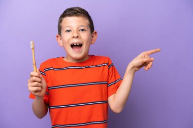 Mor arka planda dişlerini fırçalayan küçük çocuk şaşırdı ve parmağını yana çevirdi.