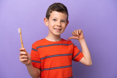 Mor arka planda dişlerini fırçalayan küçük çocuk gururlu ve kendini beğenmiş.