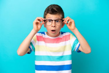 Little boy isolated on blue background With glasses and frustrated expression