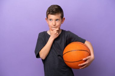 Mor arka planda izole edilmiş basketbol oynayan küçük çocuğun şüpheleri ve düşünceleri var.