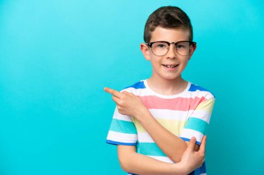 Mavi arka planda gözlüklü ve işaret eden küçük bir çocuk.