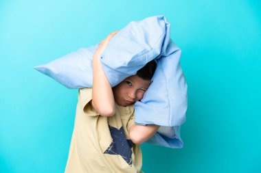 Mavi arka planda pijamalı küçük bir çocuk.