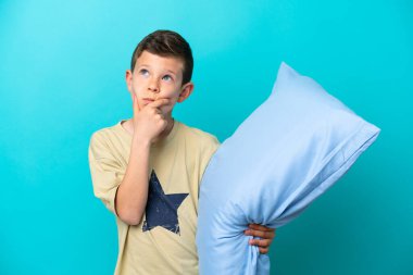 Pijamalı küçük çocuk mavi arka planda izole edilmiş.