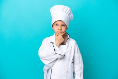 Küçük aşçı çocuk mavi arka planda izole edilmiş düşünüyor.
