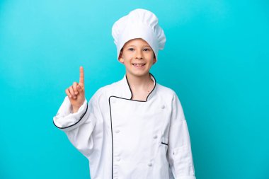 Mavi arka planda izole edilmiş küçük aşçı çocuk harika bir fikri işaret ediyor.