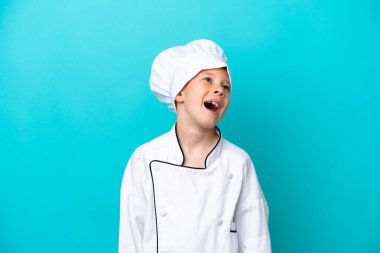 Küçük aşçı çocuk mavi arka planda yalnız gülüyor.
