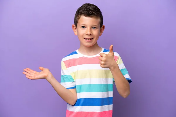 一个被隔离在紫色背景上的小男孩 手掌上握着想象中的复制空间 插入广告 竖起大拇指 — 图库照片