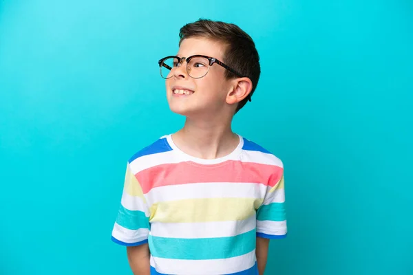 Kleine Jongen Geïsoleerd Blauwe Achtergrond Met Bril Met Gelukkige Uitdrukking — Stockfoto