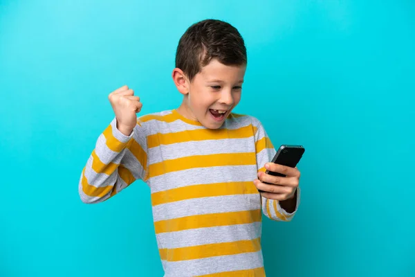 Little Boy Isolated Blue Background Using Mobile Phone Doing Victory — Stock Photo, Image