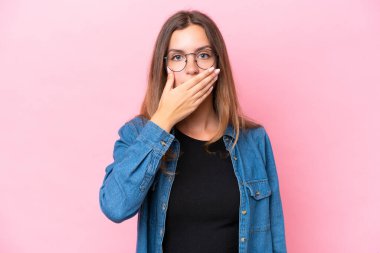Pembe arka planda izole edilmiş, ağzı elle kaplanmış beyaz bir kadın.