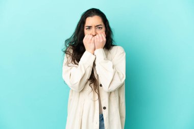 Mavi arka planda izole edilmiş beyaz bir kadın gergin ve korkmuş bir şekilde elleriyle suni teneffüs yapıyor.